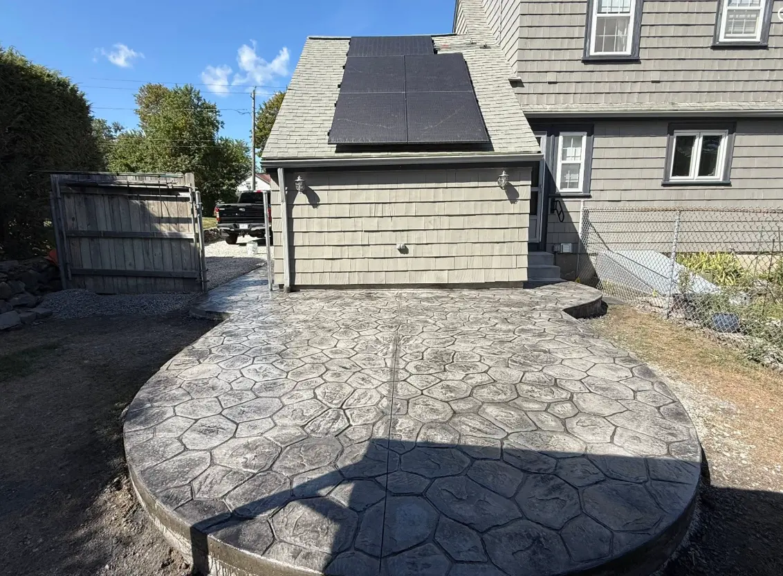 Rounded stamped concrete patio with a stone pattern in front of a garage