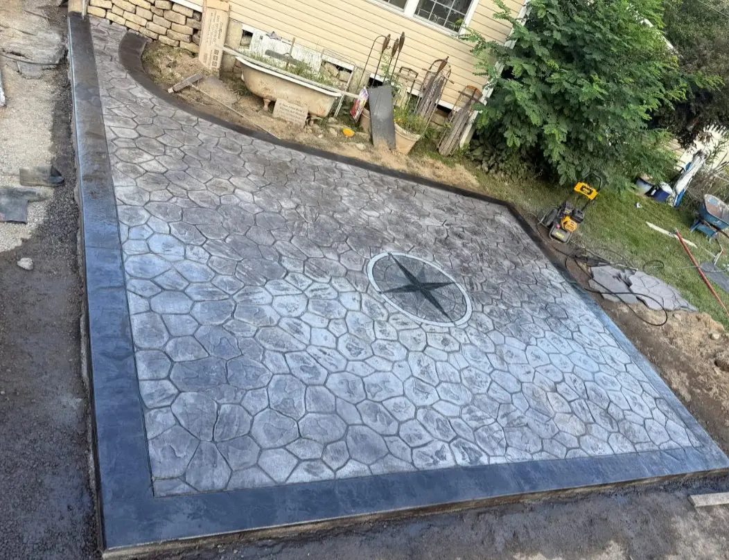Large stamped concrete patio with a stone pattern and a compass-star medallion in the center