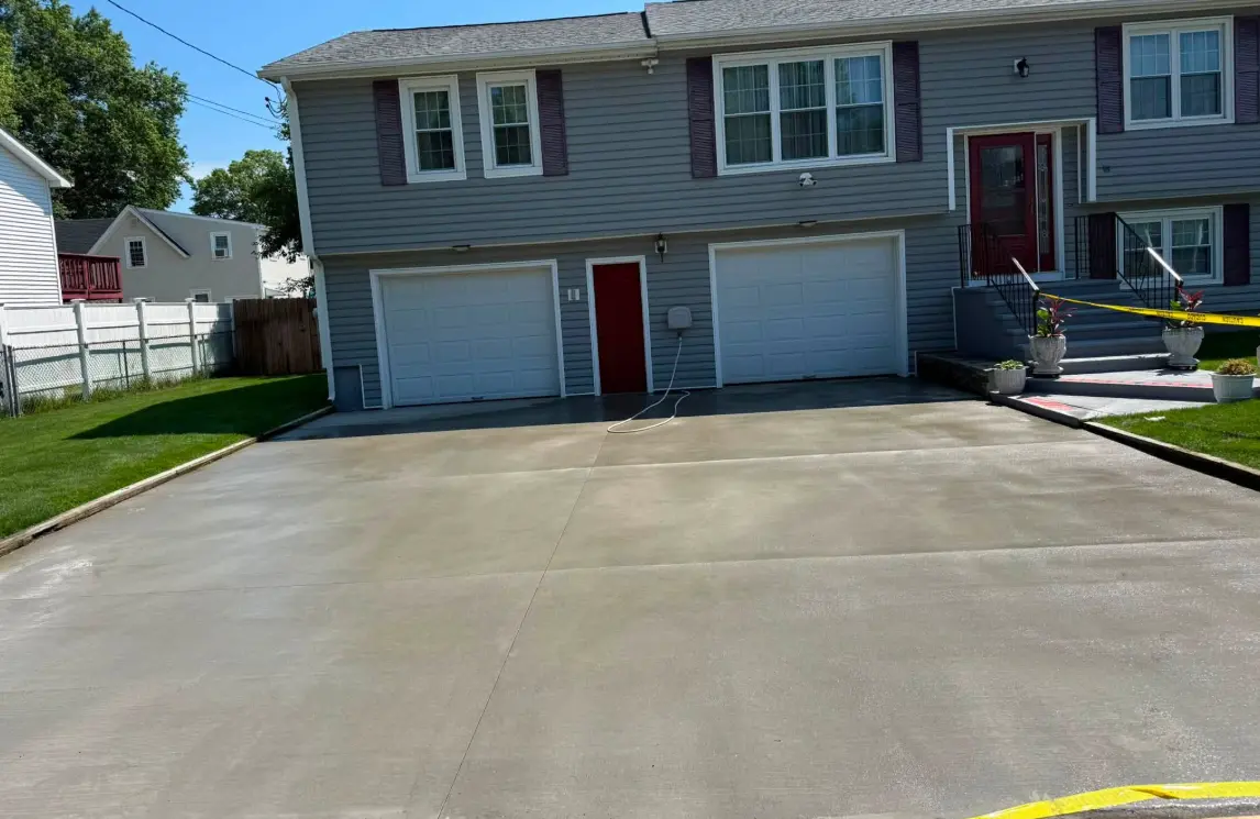 Smooth-finished concrete driveway leading to a two-car garage