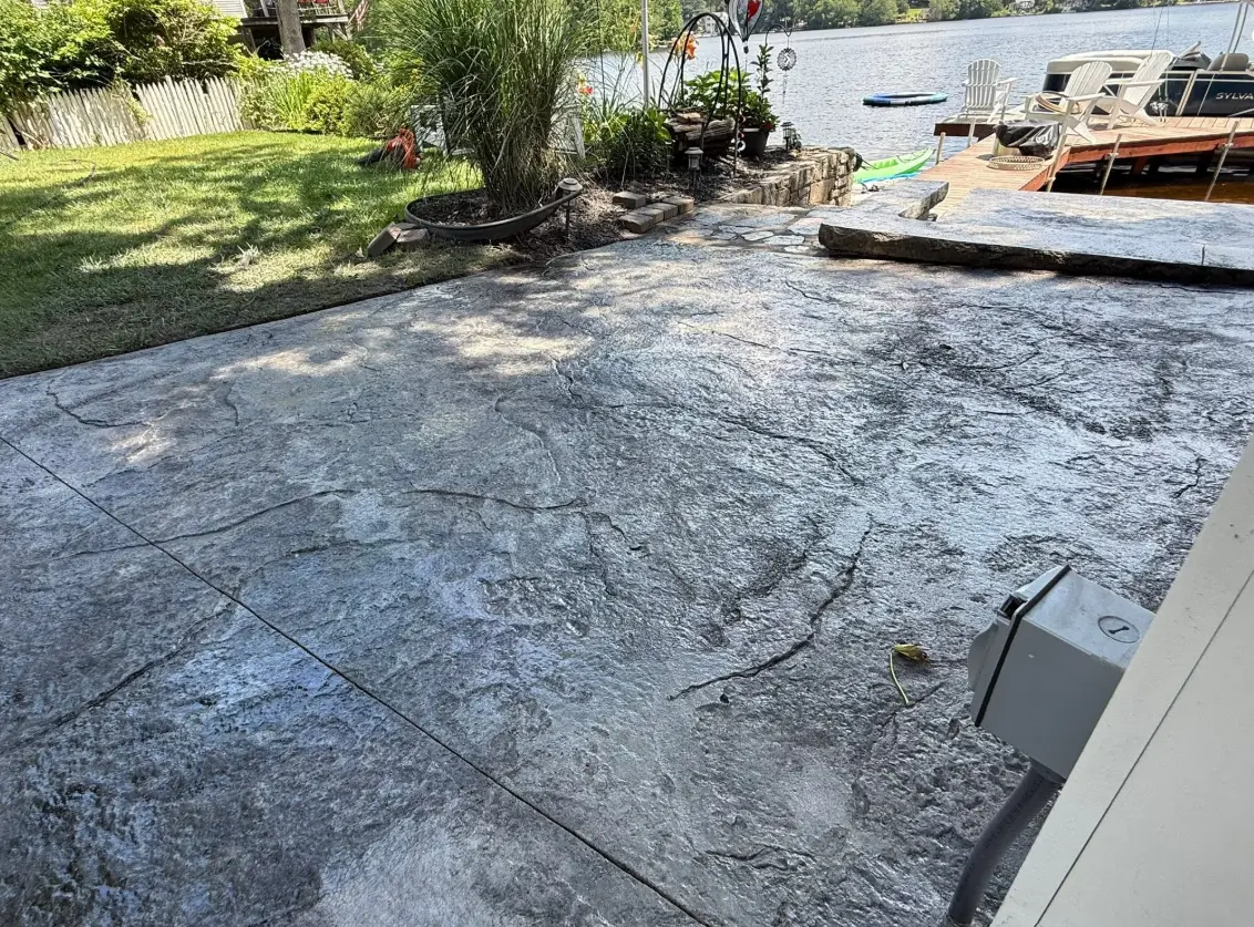 Stamped concrete patio with a slate-like texture beside a lake and dock